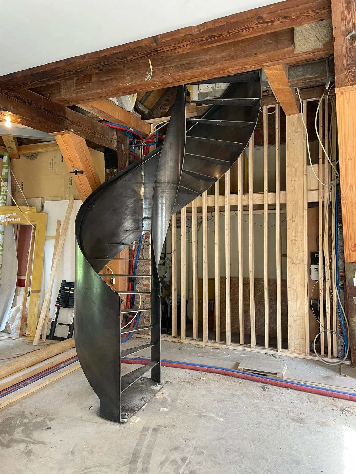 Stalen spiltrap met gebogen balustrade tussen de houten balken van de molen